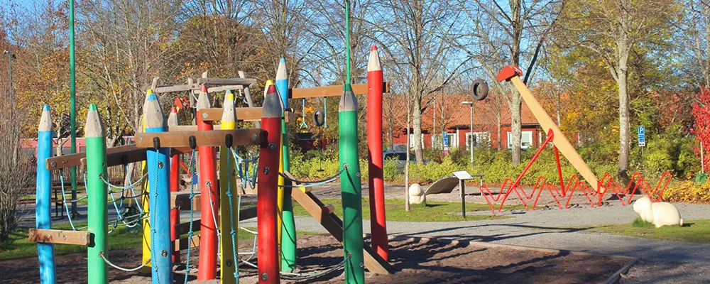 Foto på en lekpark där man ser en färgglad balansgång och en linbana. 
