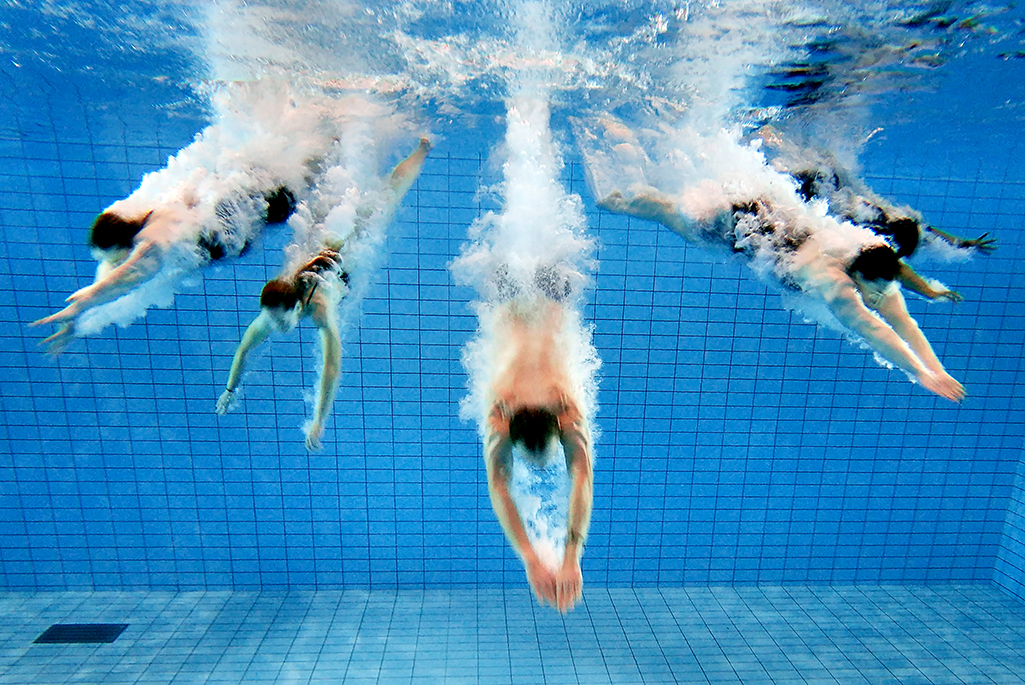 Foto på personer som dyker i en pool.