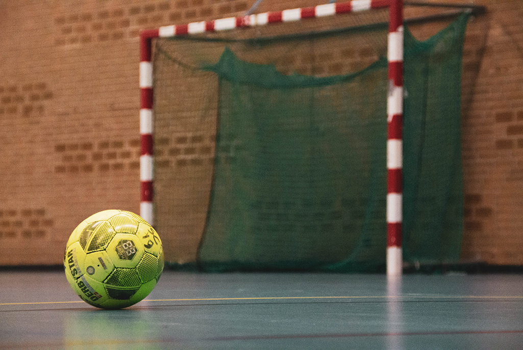 En fotboll liggandes på golvet vid en fotbollsplan inomhus.